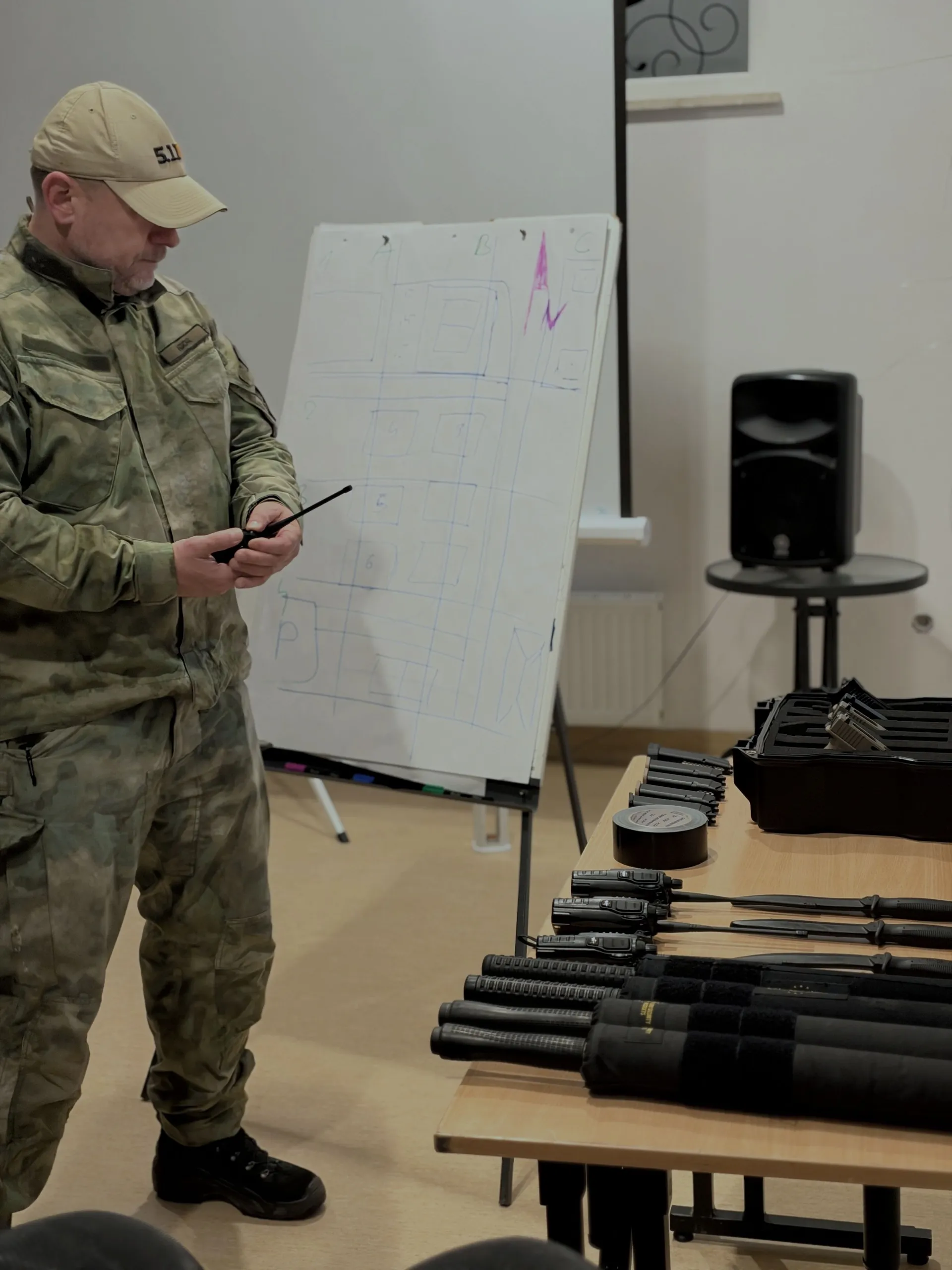 Instruktor DefendU prowadzi odprawę przy tablicy przed eventem