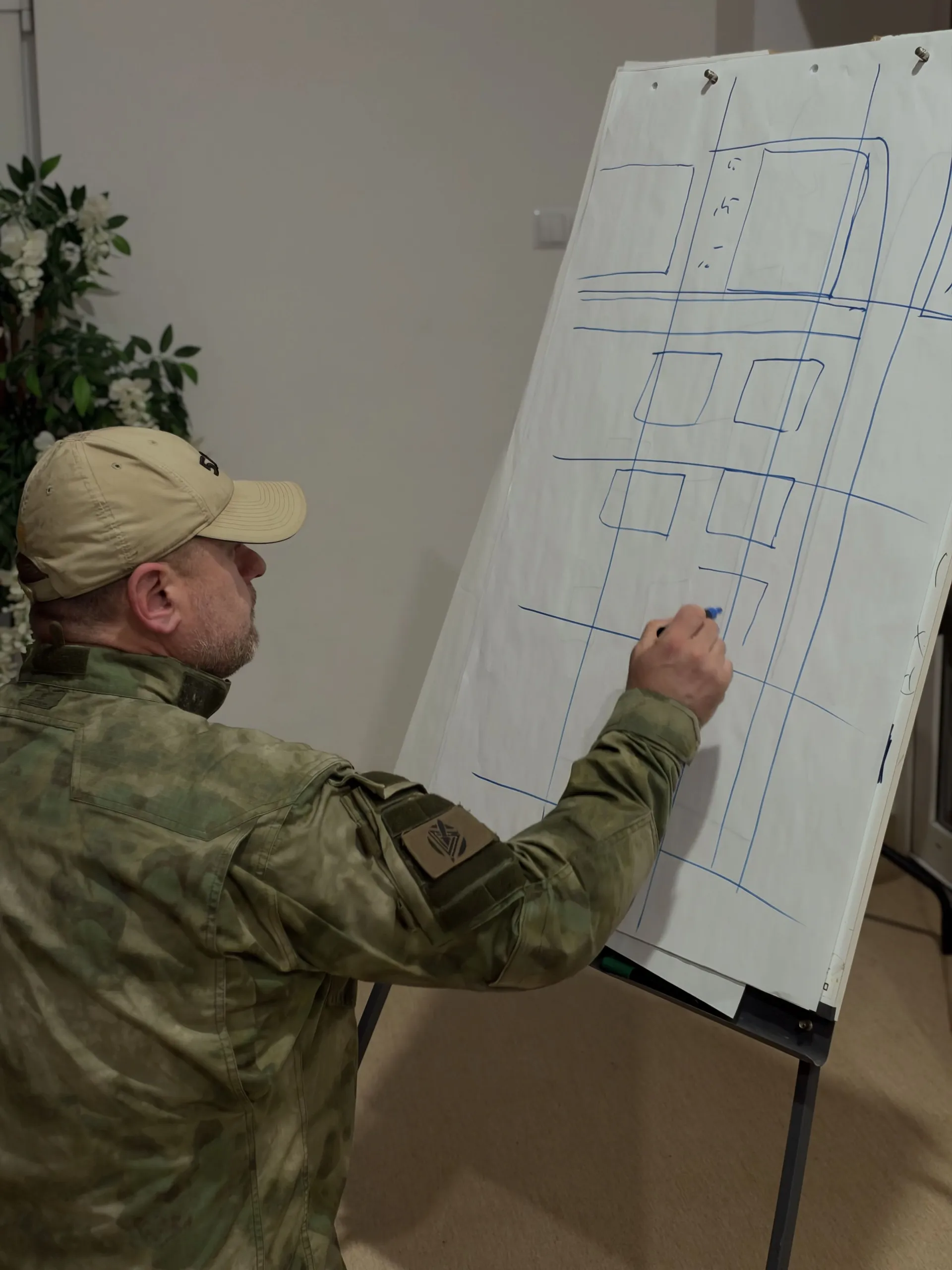 Instruktor DefendU rozrysowuje plan na tablicy podczas prelekcji